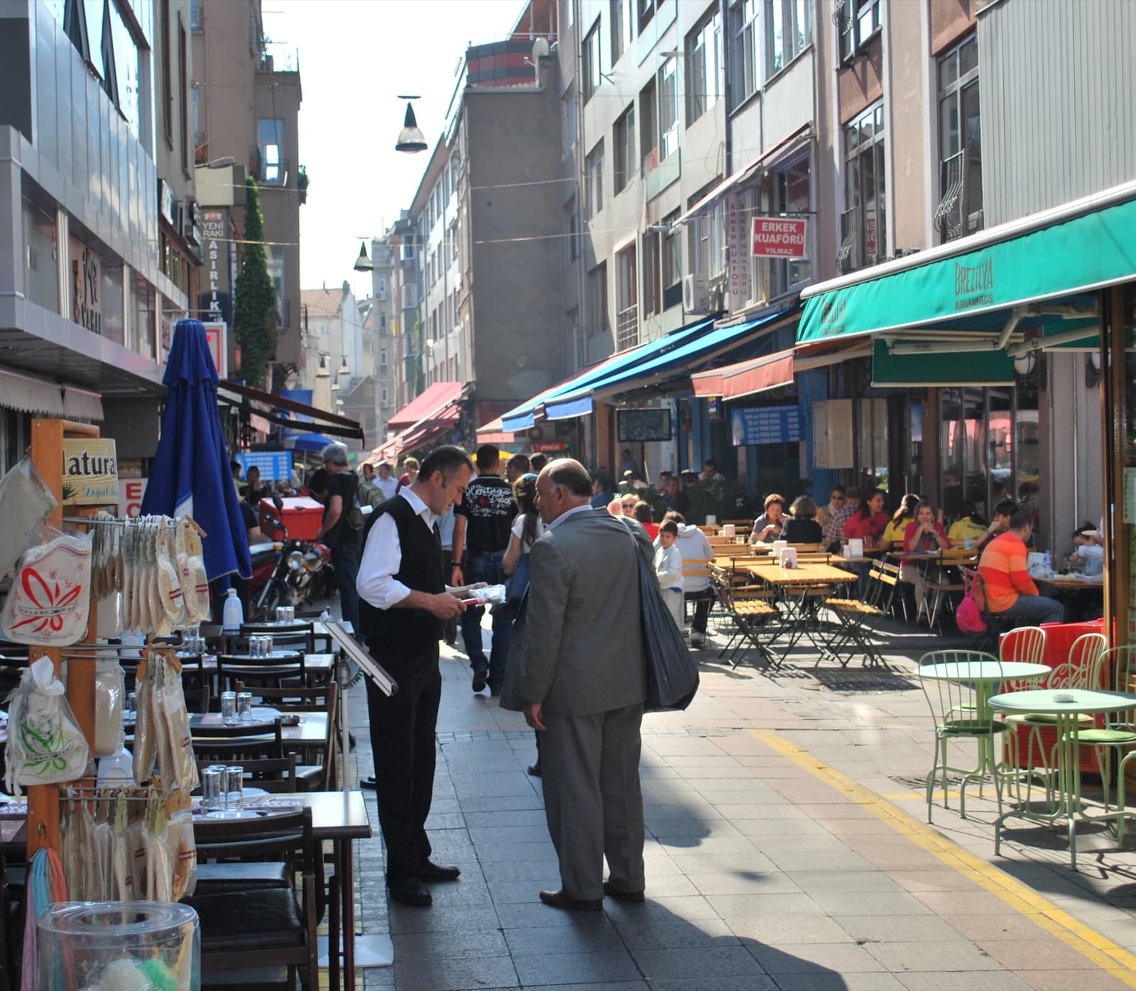 Calle Guneslibahce en el mercado de Kadikoy con puestos de fruta, restaurantes y vecinos paseando