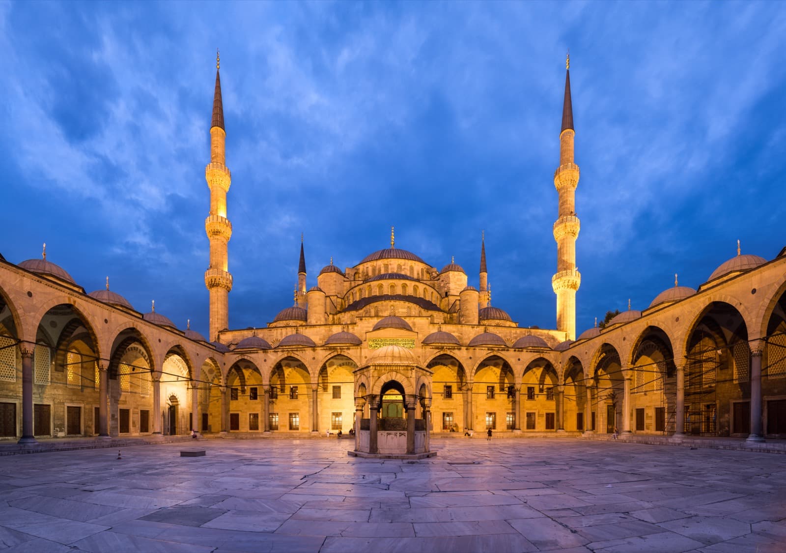 Patio de la Mezquita Azul de Estambul al atardecer con sus cúpulas y minaretes iluminados